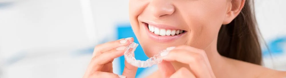 Woman holding a pair of clear orthodontic aligner trays — dental clinic in Buderim, QLD