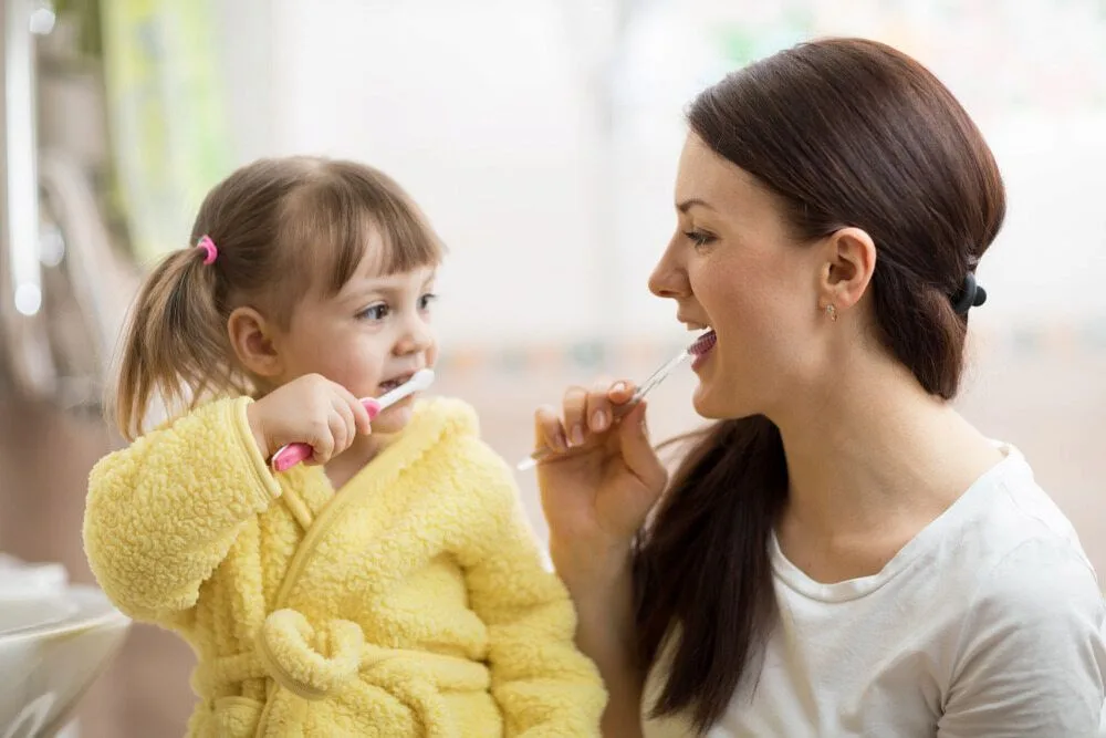 A woman and a little girl are brushing their teeth together — dental clinic in Buderim, QLD