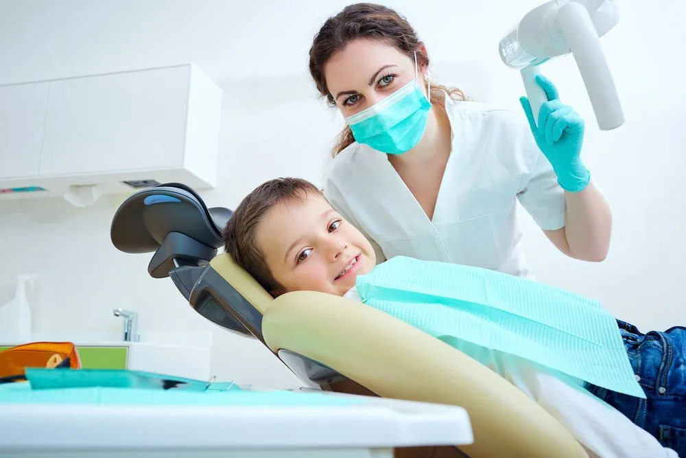 A young child smiling in the dental chair beside a dentist — dental clinic in Buderim, QLD