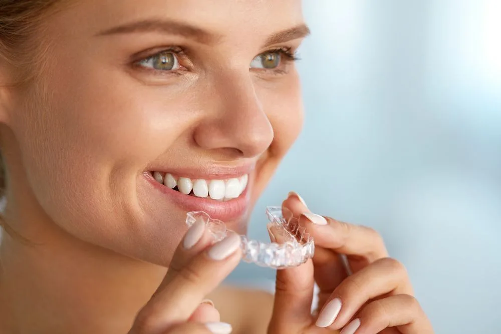 Woman holding a clear aligner tray and smiling — dental clinic in Buderim, QLD