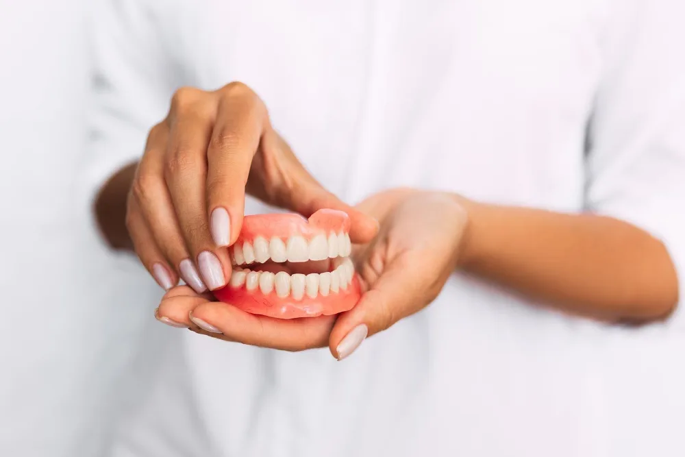 Dentist holding a full set of upper and lower dentures — dental clinic in Buderim, QLD