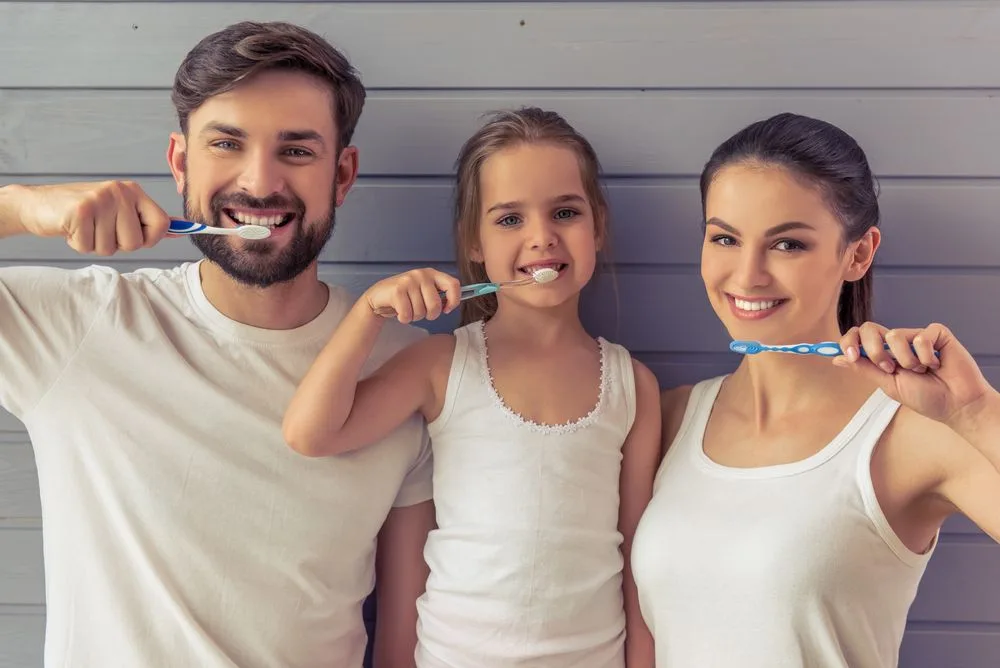 A father, daughter and mother brushing their teeth together — dental clinic in Buderim, QLD