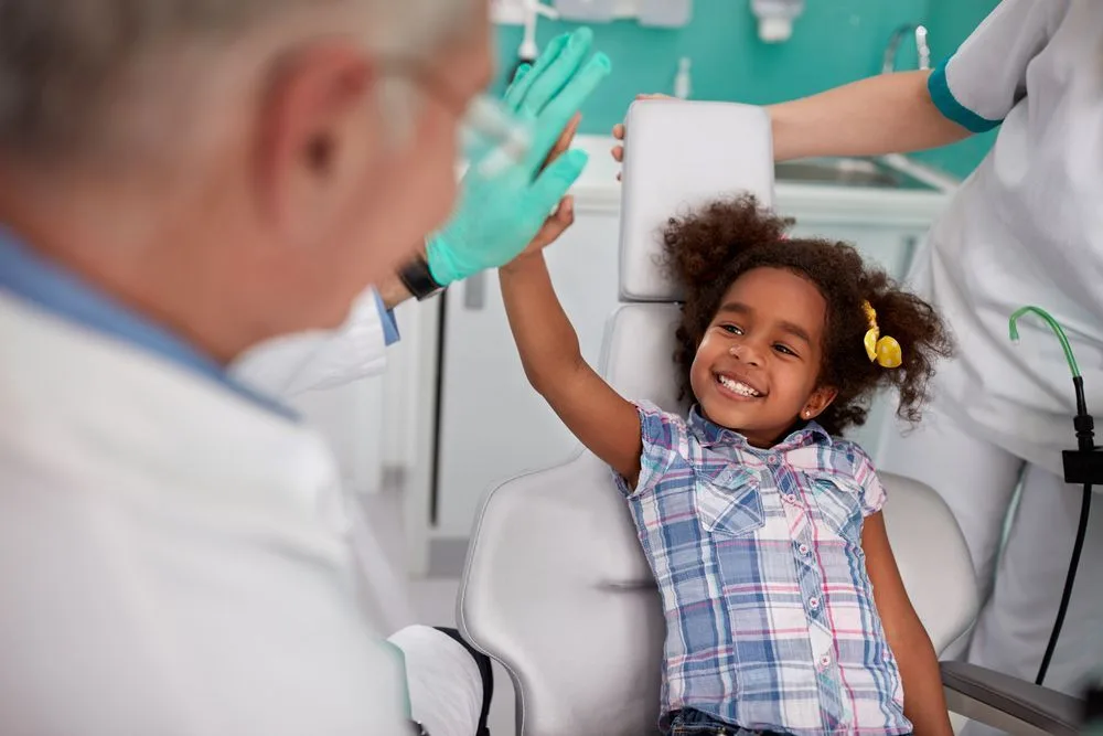 Young girl giving the dentist a high five in the dental chair — dental clinic in Buderim, QLD