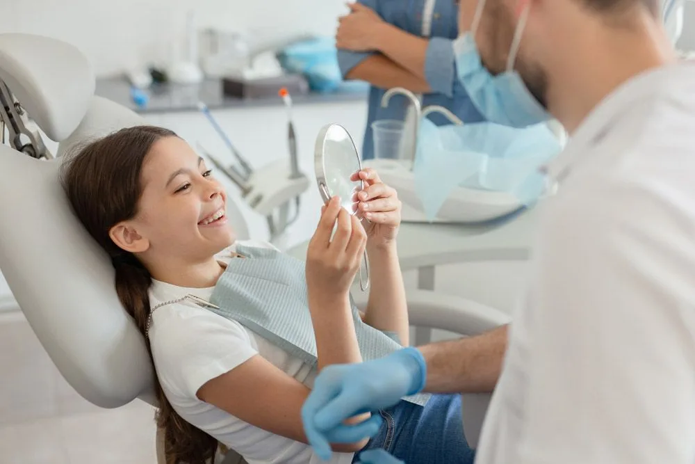 Girl looking at her smile in a mirror after a dental procedure — dental clinic in Mooloolaba, QLD