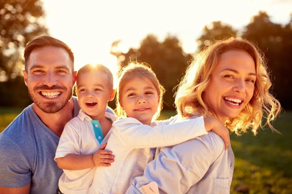 Happy family of four smiling outdoors at sunset — dental clinic in Buderim, QLD