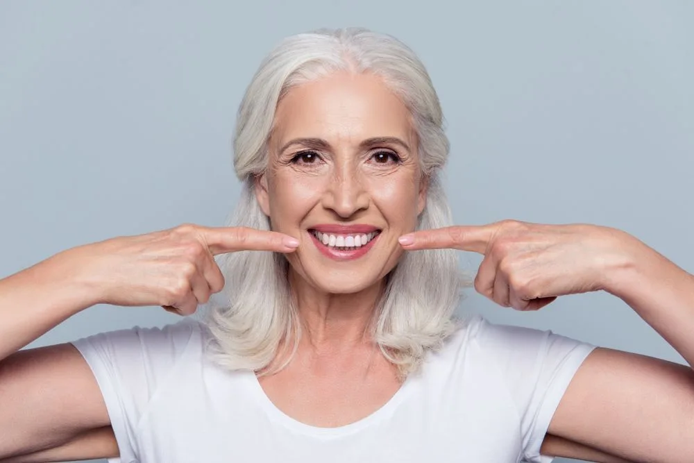 Older woman pointing to her healthy smile — dental clinic in Buderim, QLD