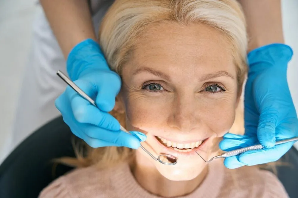 A woman is smiling while having her teeth examined by a dentist — dental clinic in Buderim, QLD