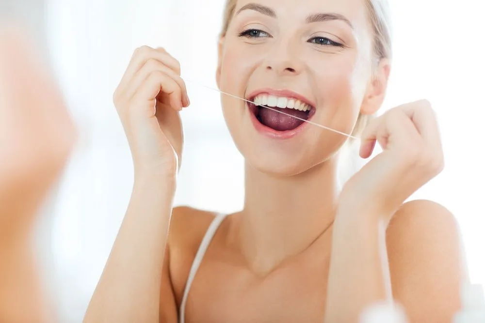 Woman flossing her teeth in front of a mirror — dental clinic in Buderim, QLD
