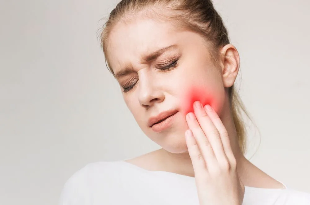 Woman holding her jaw in discomfort — dental clinic in Buderim, QLD